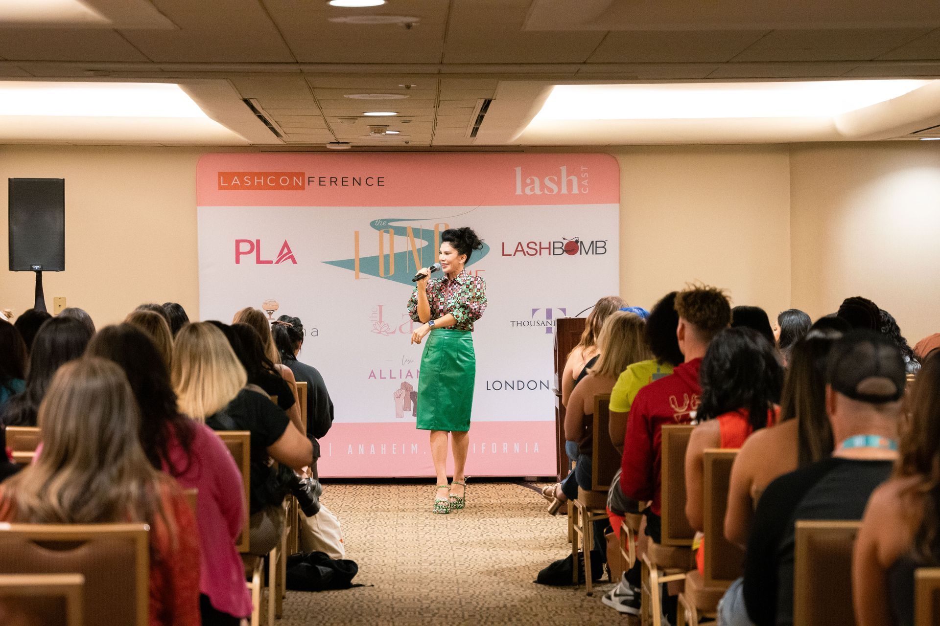 A woman is standing in front of a crowd of people giving a presentation.