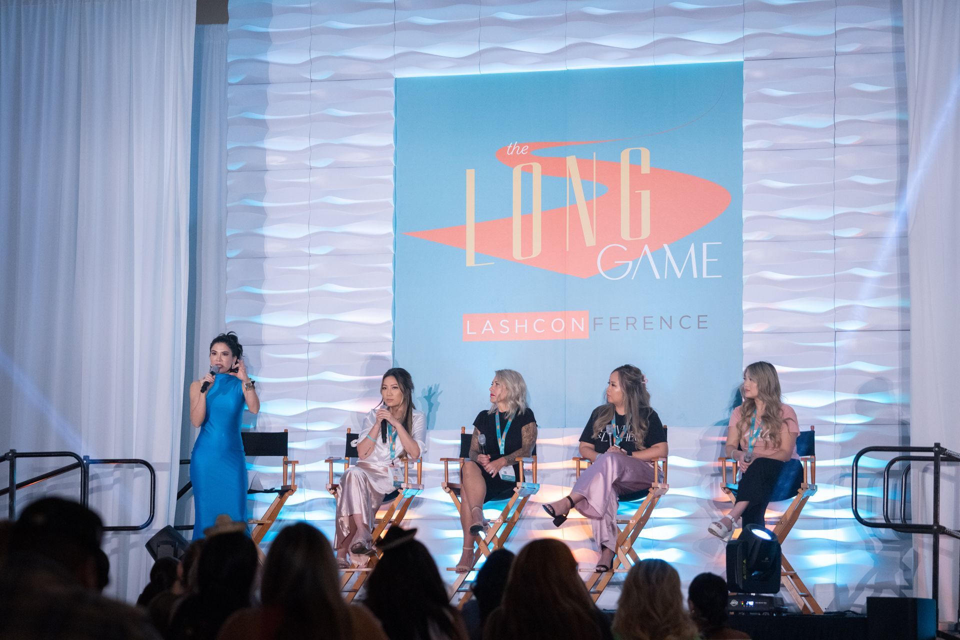 A group of women are sitting on a stage talking to a crowd.