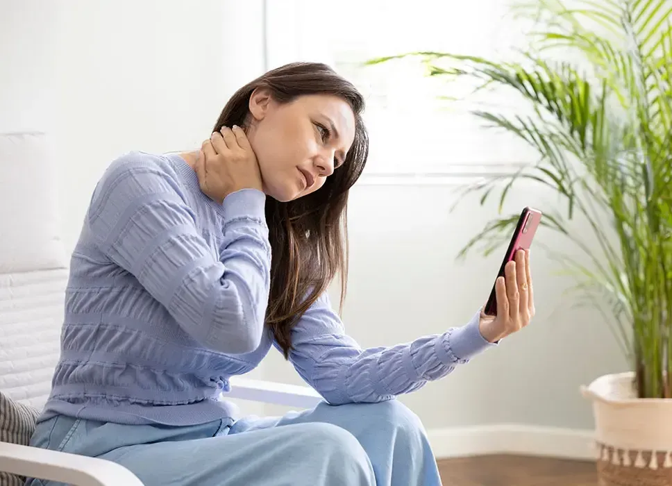 A woman is sitting in a chair looking at her phone.