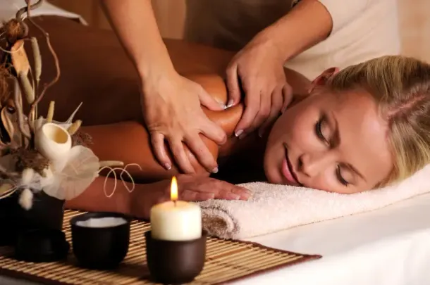 A woman is getting a massage with a candle in the foreground