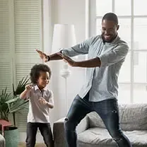 A man and a child are dancing in a living room.