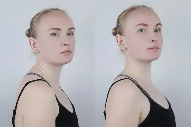 A woman in a black tank top is standing in front of a white wall.