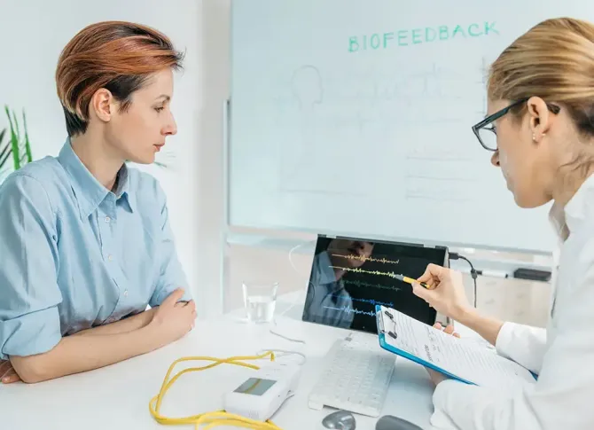 A woman is sitting at a table talking to a doctor.