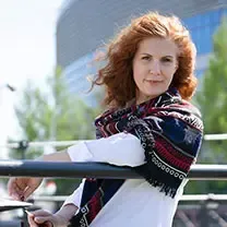A woman wearing a scarf is leaning on a railing.