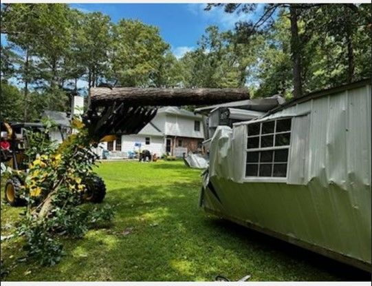 A tree has fallen on a house and a trailer.