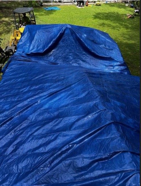 A large blue tarp is laying on the grass