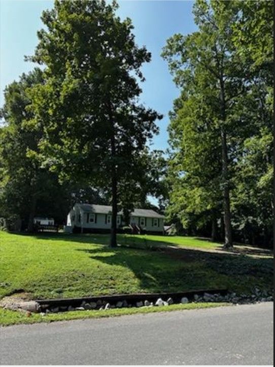 A house sits in the middle of a lush green field surrounded by trees