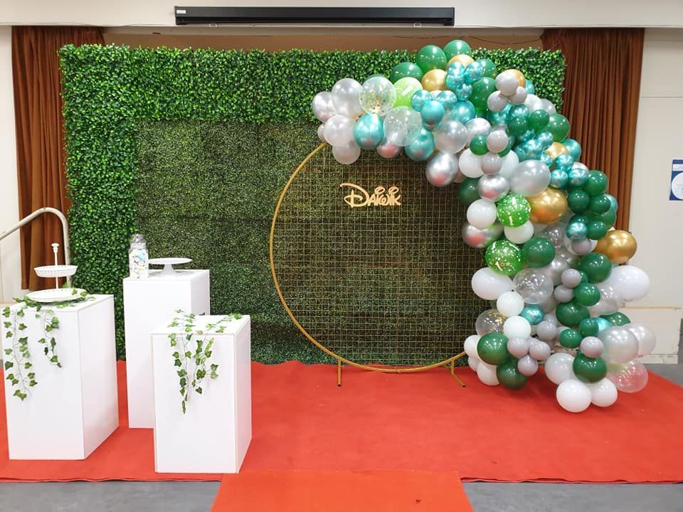 A bunch of balloons are sitting on a red carpet in front of a green wall.