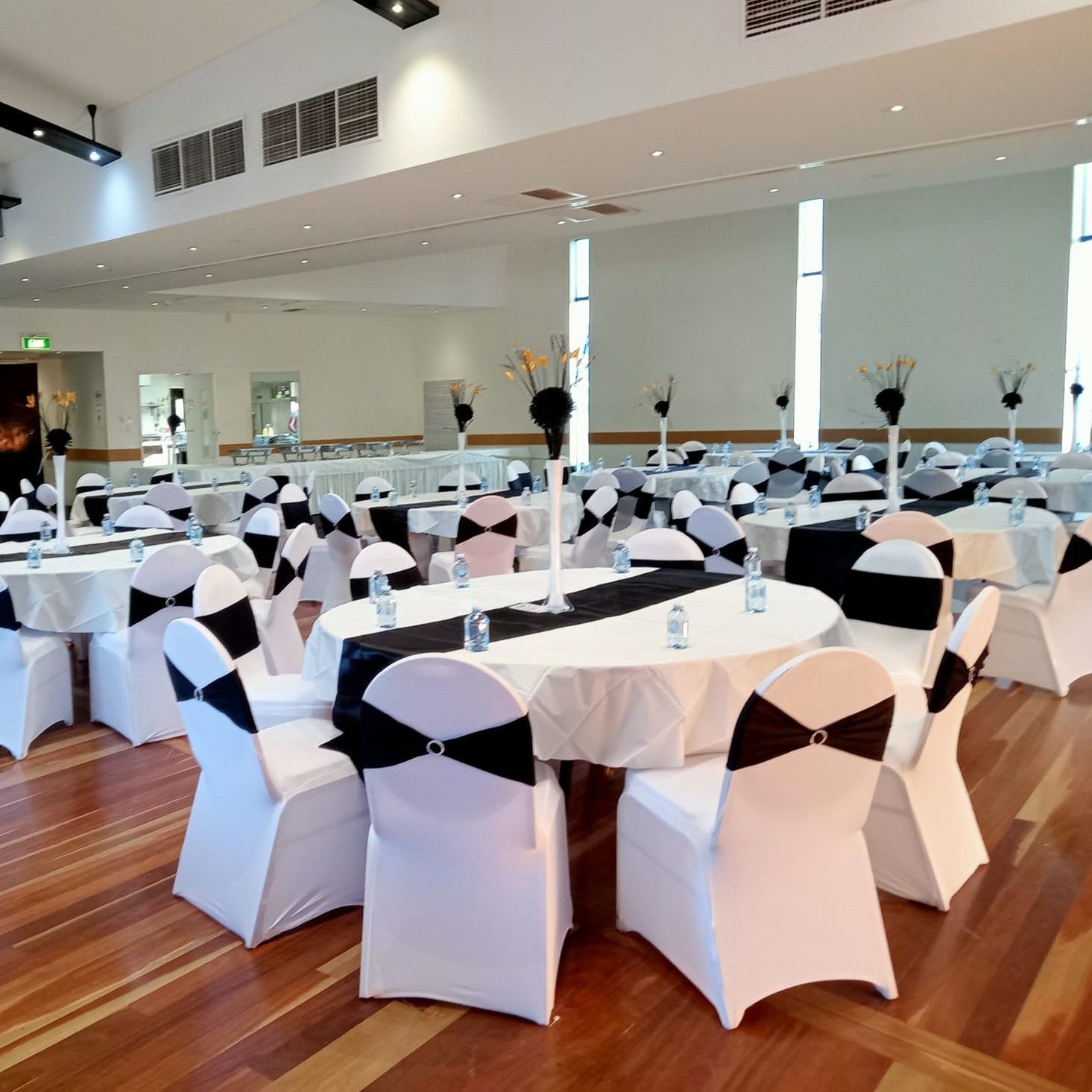A large room with tables and chairs set up for a wedding reception