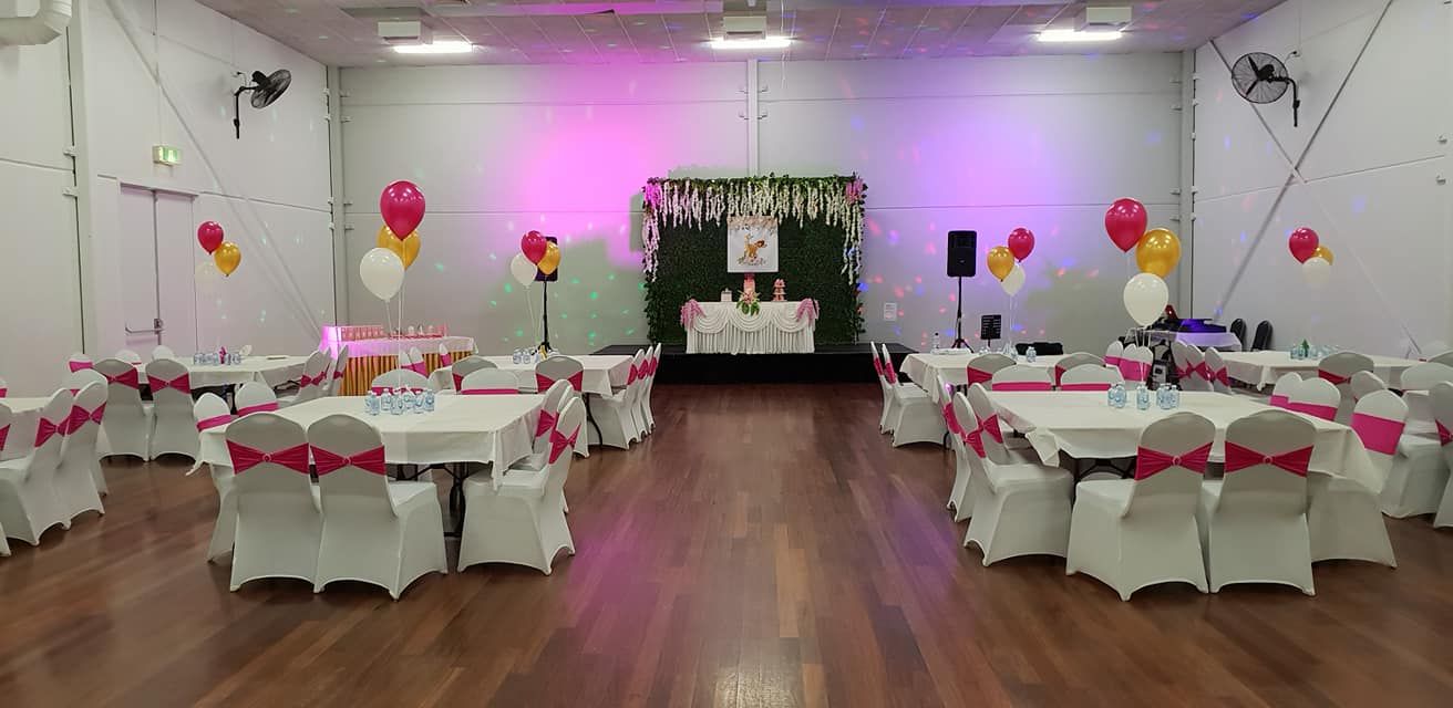 A large room filled with tables and chairs decorated for a party.