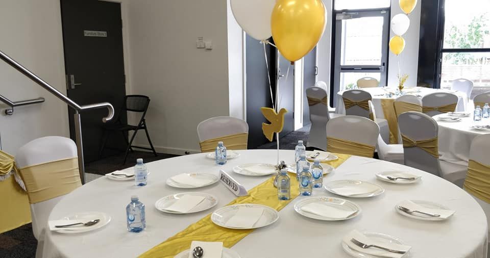 A table with plates , utensils , and balloons on it in a room.