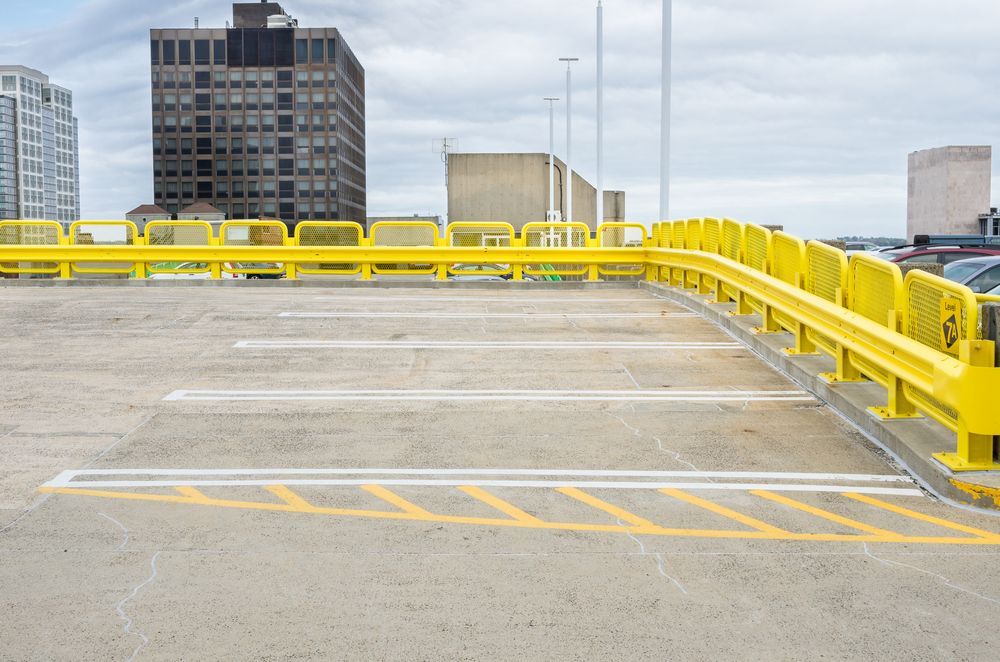 An Empty Parking Garage With a Yellow Railing and a City in the Background — Central Coast Storage Solutions in Gosford, NSW