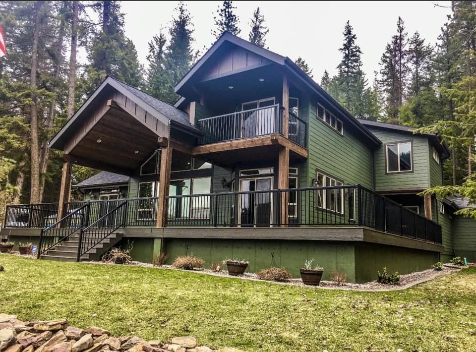 Rustic house with beam accents on the covered back deck and balcony on treed property.
