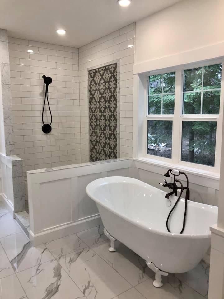 White modern bathroom with clawfoot tub, black fixtures, and tiled shower.