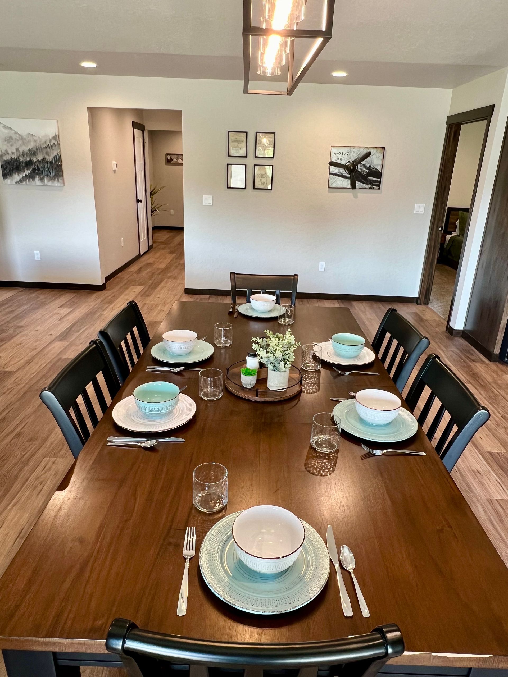 Dining table set for a meal, centered under a light fixture.