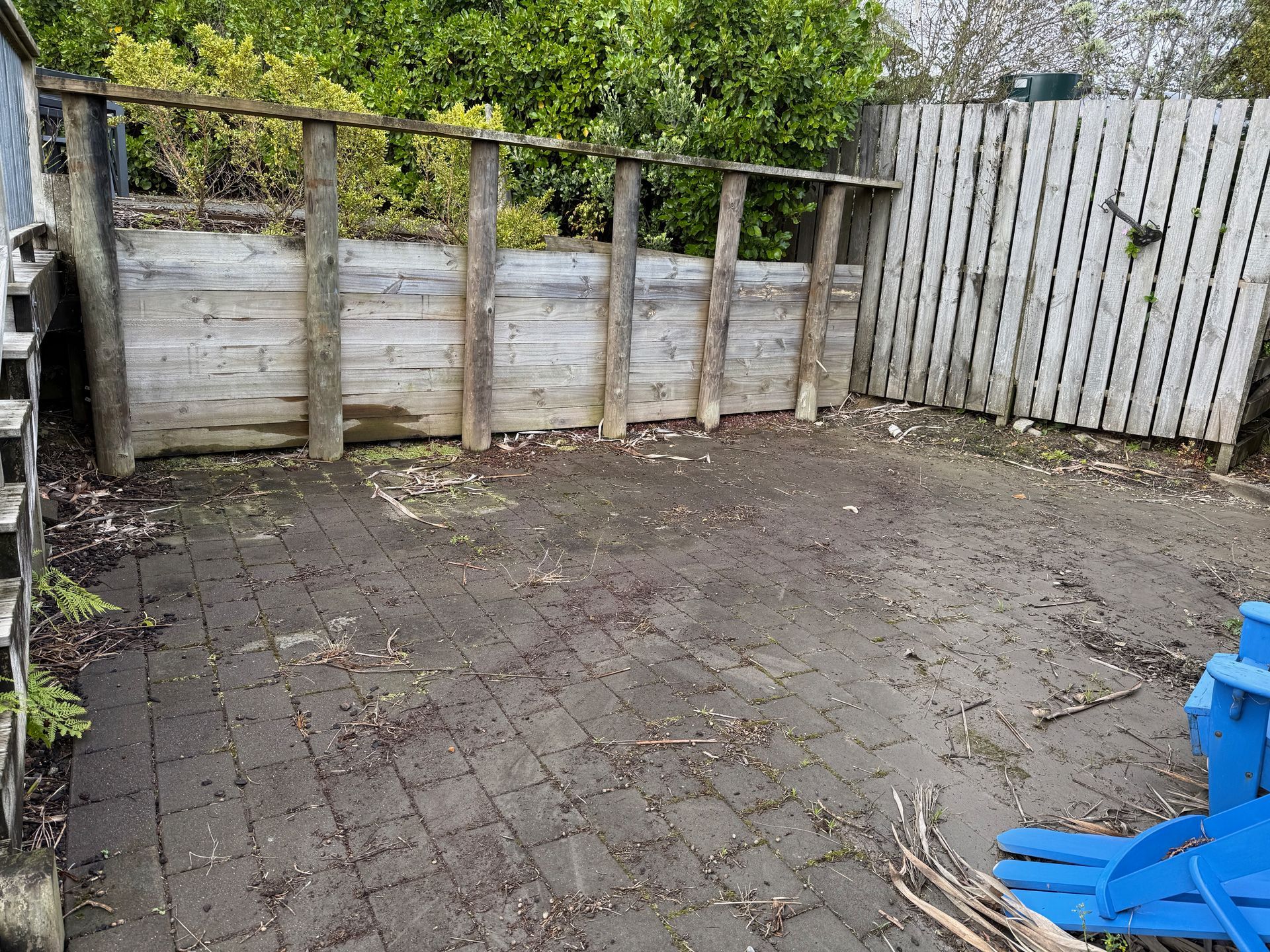 A weathered wooden patio with a wooden fence and a small wooden structure.