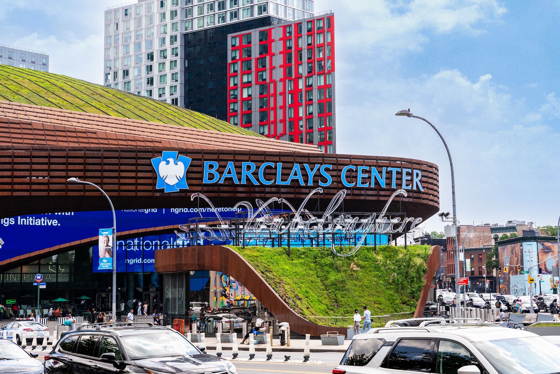 The barclays center is a large building with a lot of cars parked in front of it.