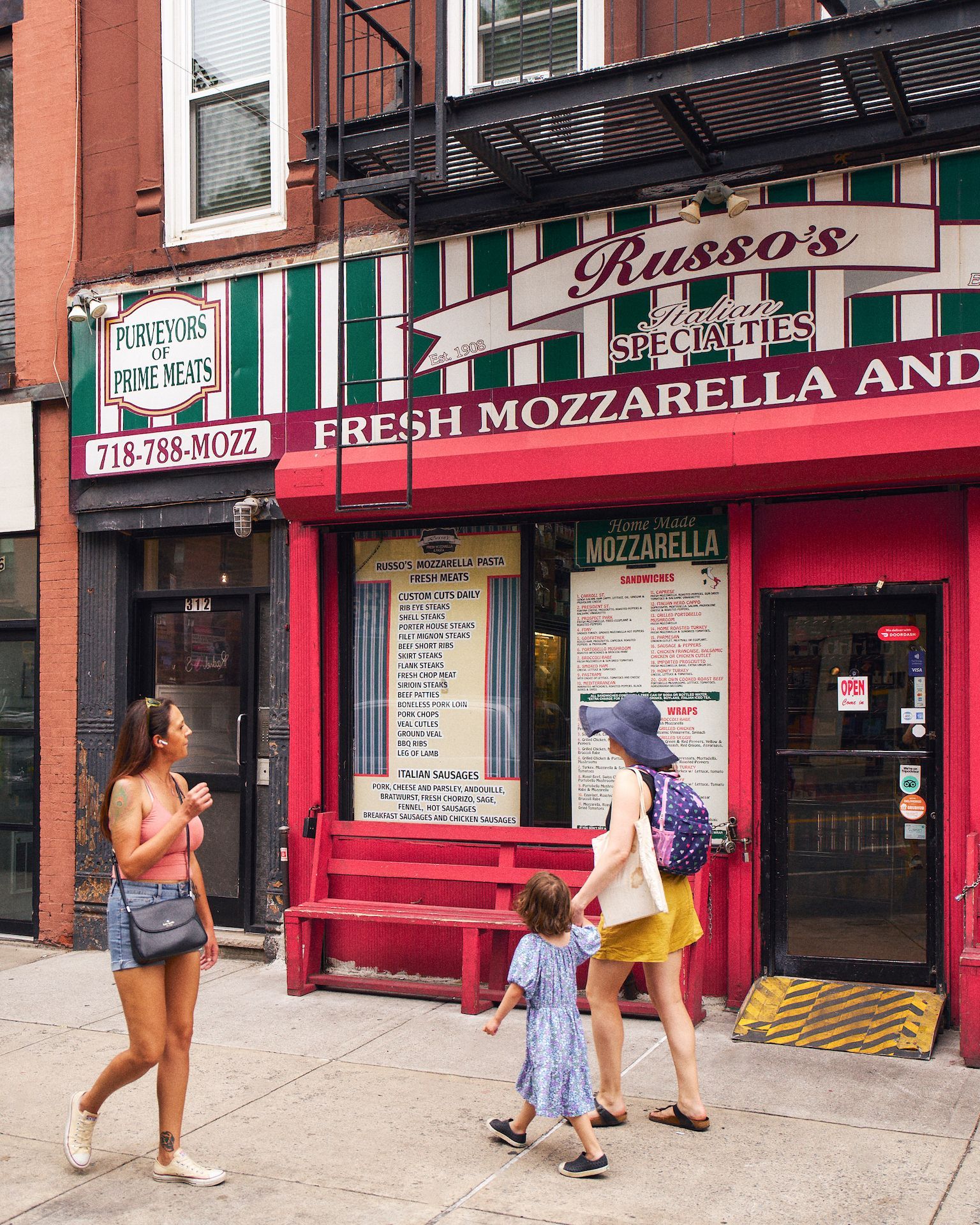 A group of people are walking in front of a restaurant called russo 's