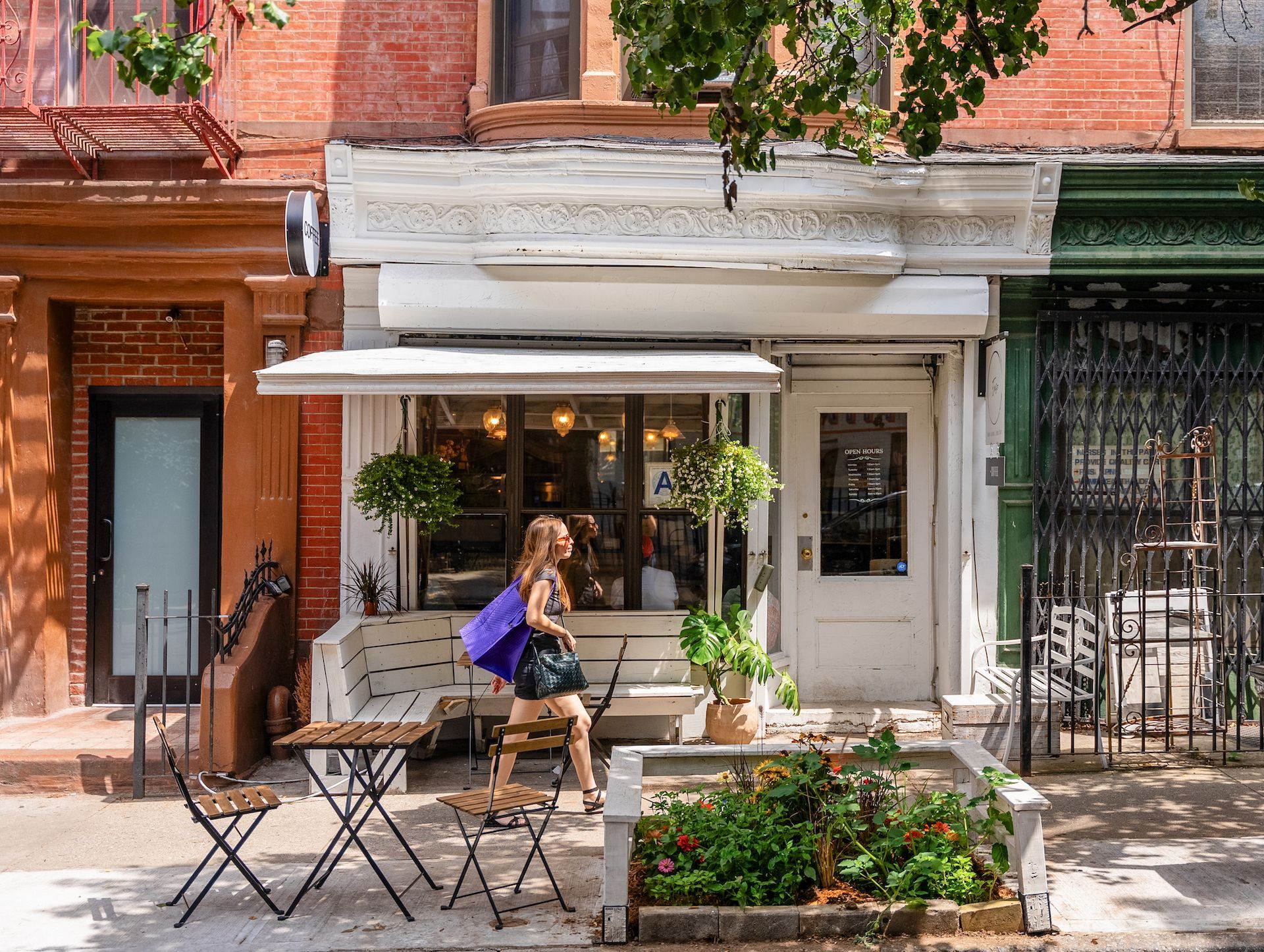 A woman is sitting at a table outside of a restaurant.