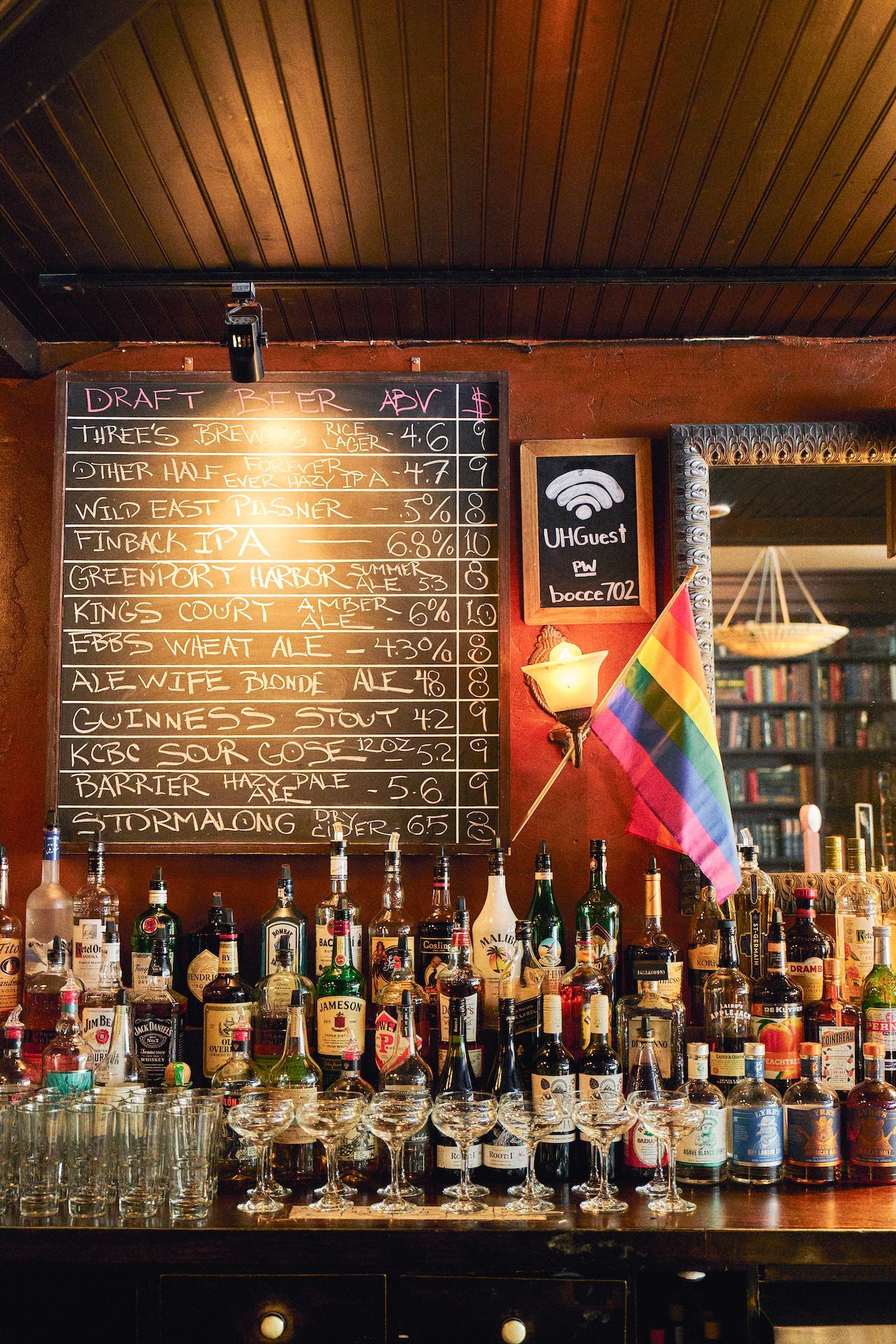 A bar with a rainbow flag and a menu on the wall