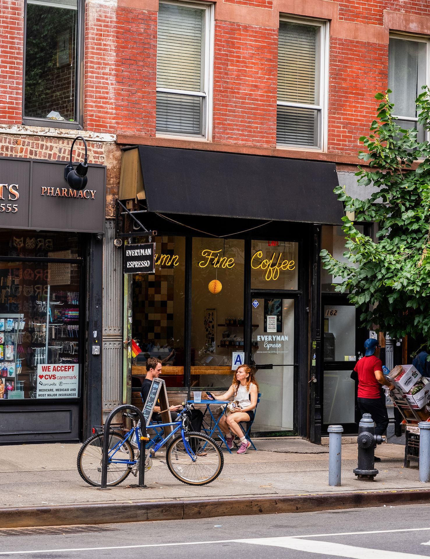 A woman sits at a table outside of a coffee shop