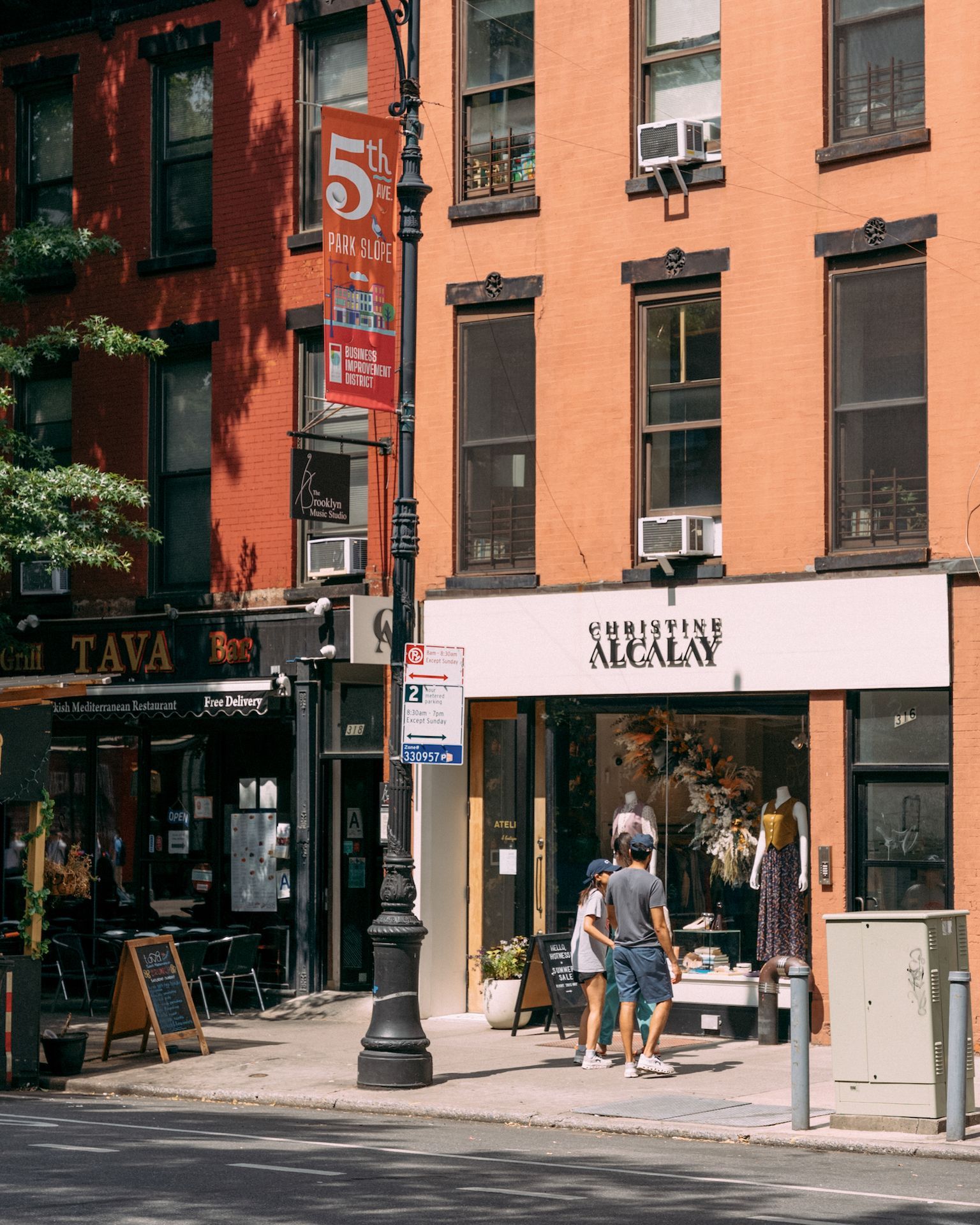 A group of people are walking down a street in front of a building that has the number 5 on it