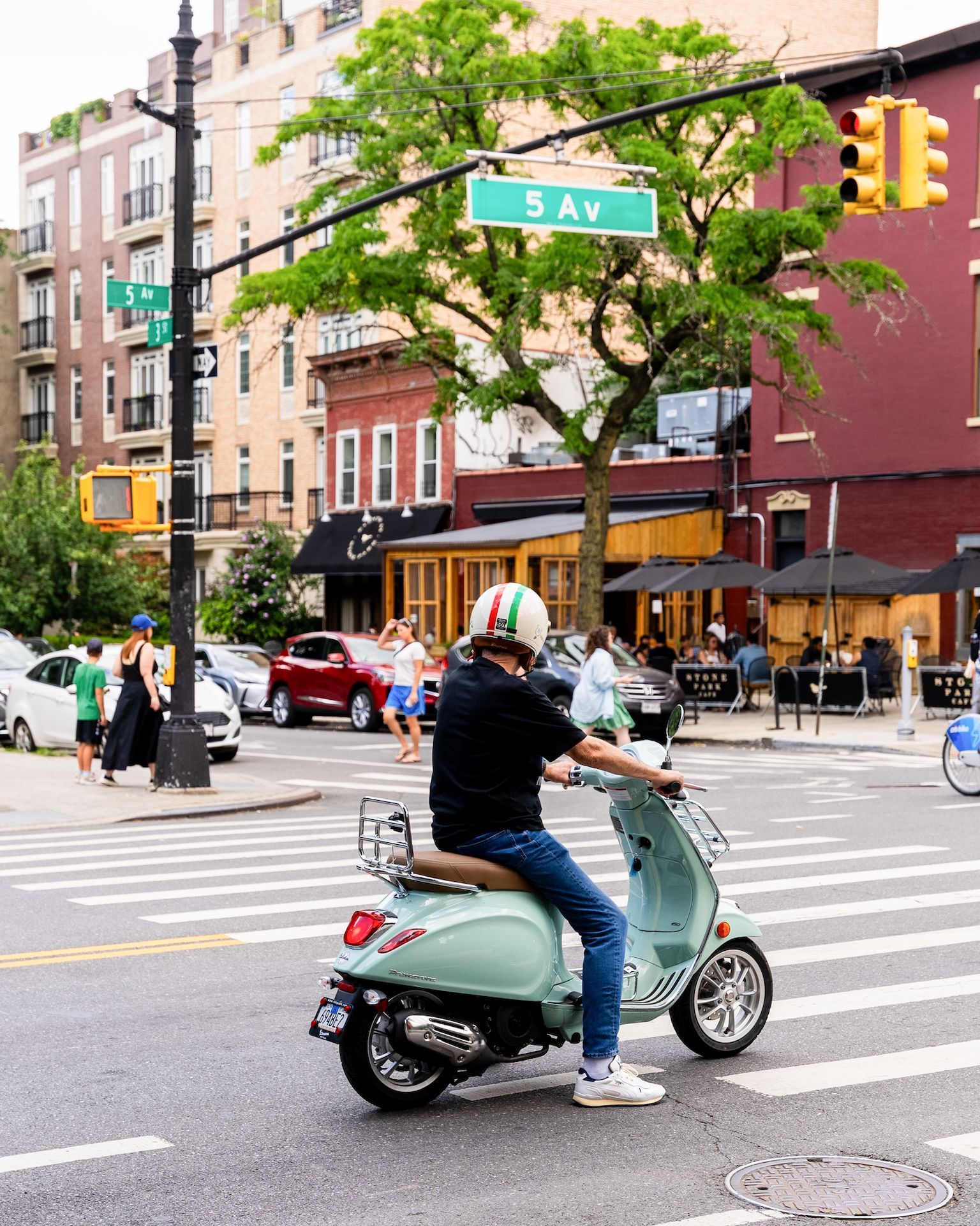 A man is riding a scooter down 5th ave