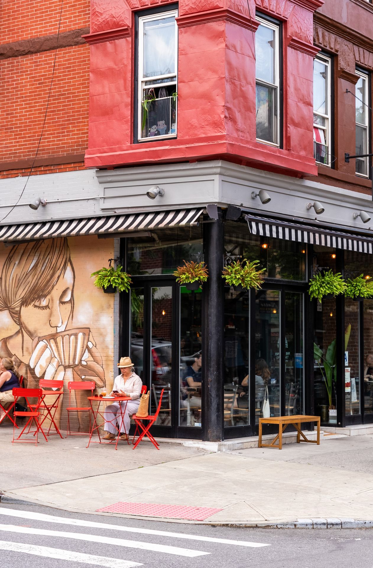 A woman is sitting at a table outside of a restaurant.