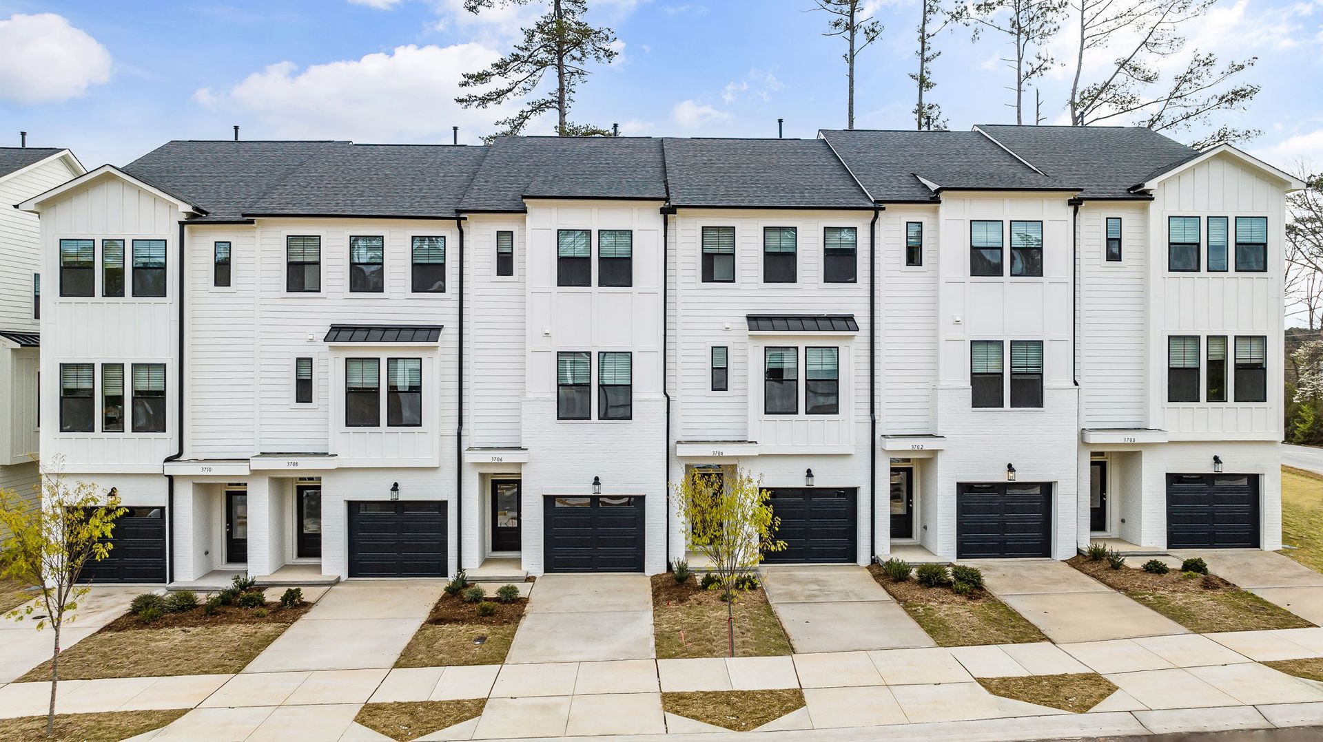 a row of white apartment buildings with black garage doors