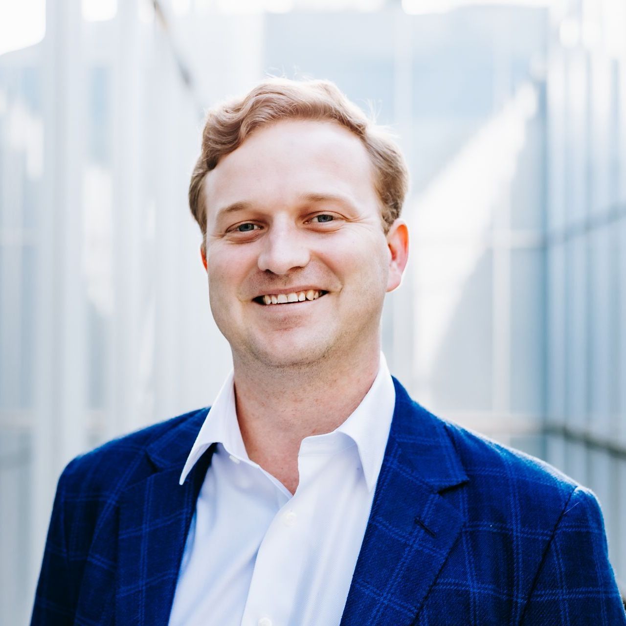 A man in a blue suit and white shirt is smiling for the camera