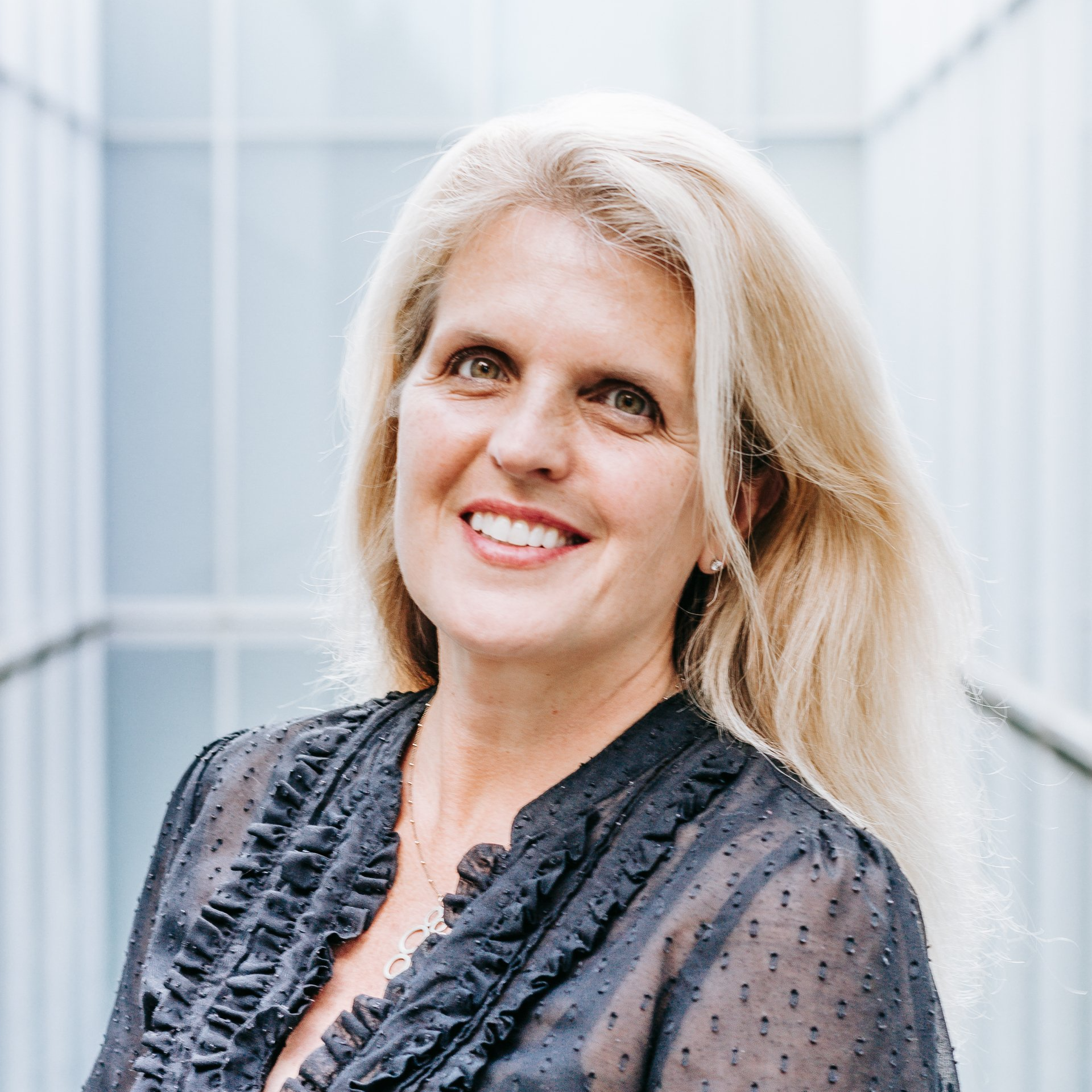 a woman in a black blouse is smiling for the camera .