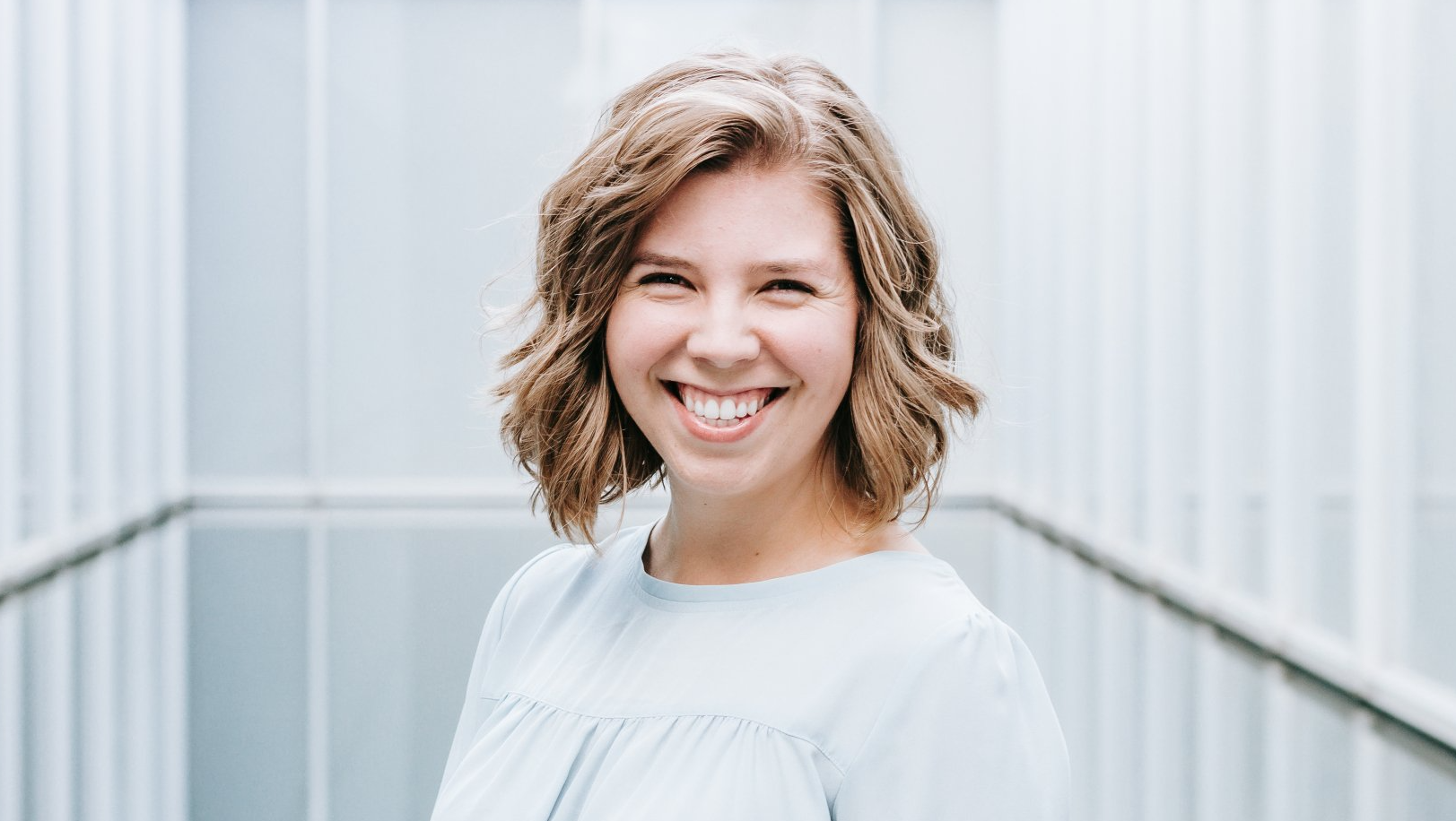 a woman is smiling for the camera while standing on a bridge .