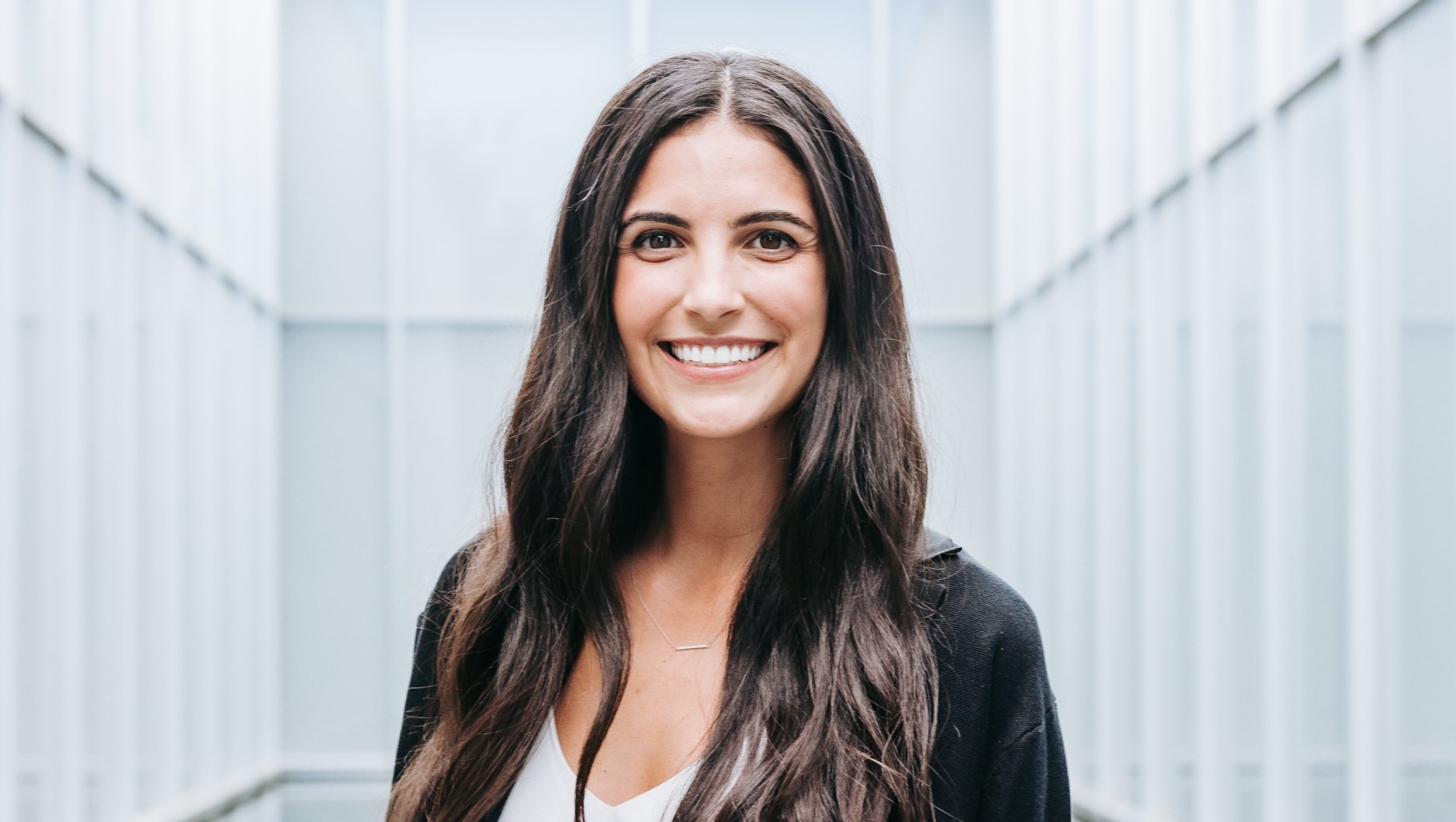 a woman with long hair is smiling for the camera in front of a building .