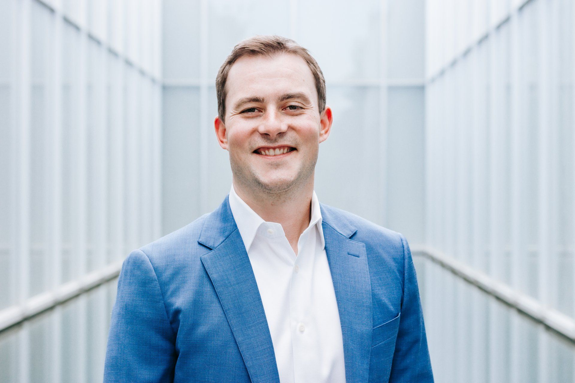 a man in a blue suit and white shirt is smiling for the camera .