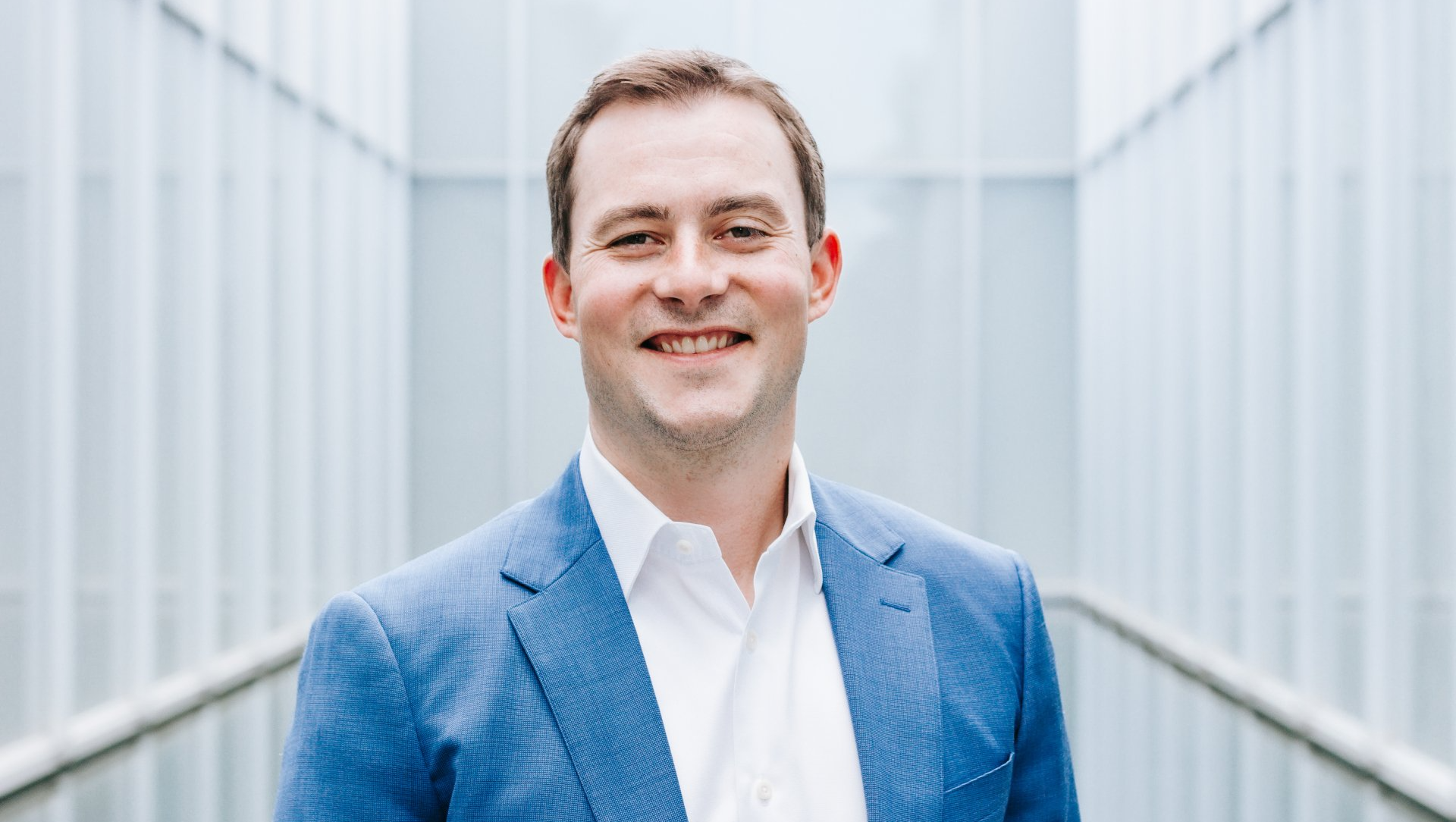a man in a blue suit and white shirt is smiling for the camera .