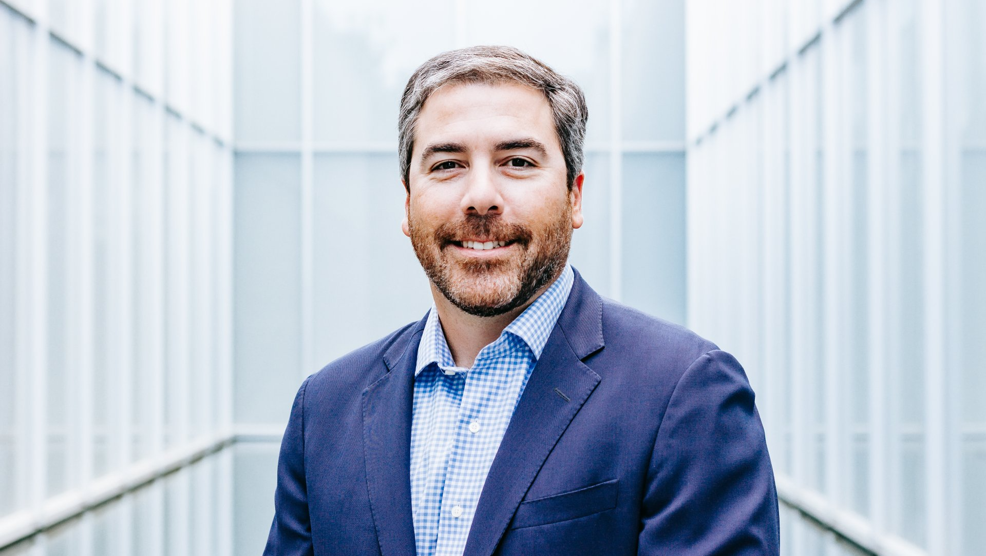 a man in a suit and plaid shirt is smiling for the camera .