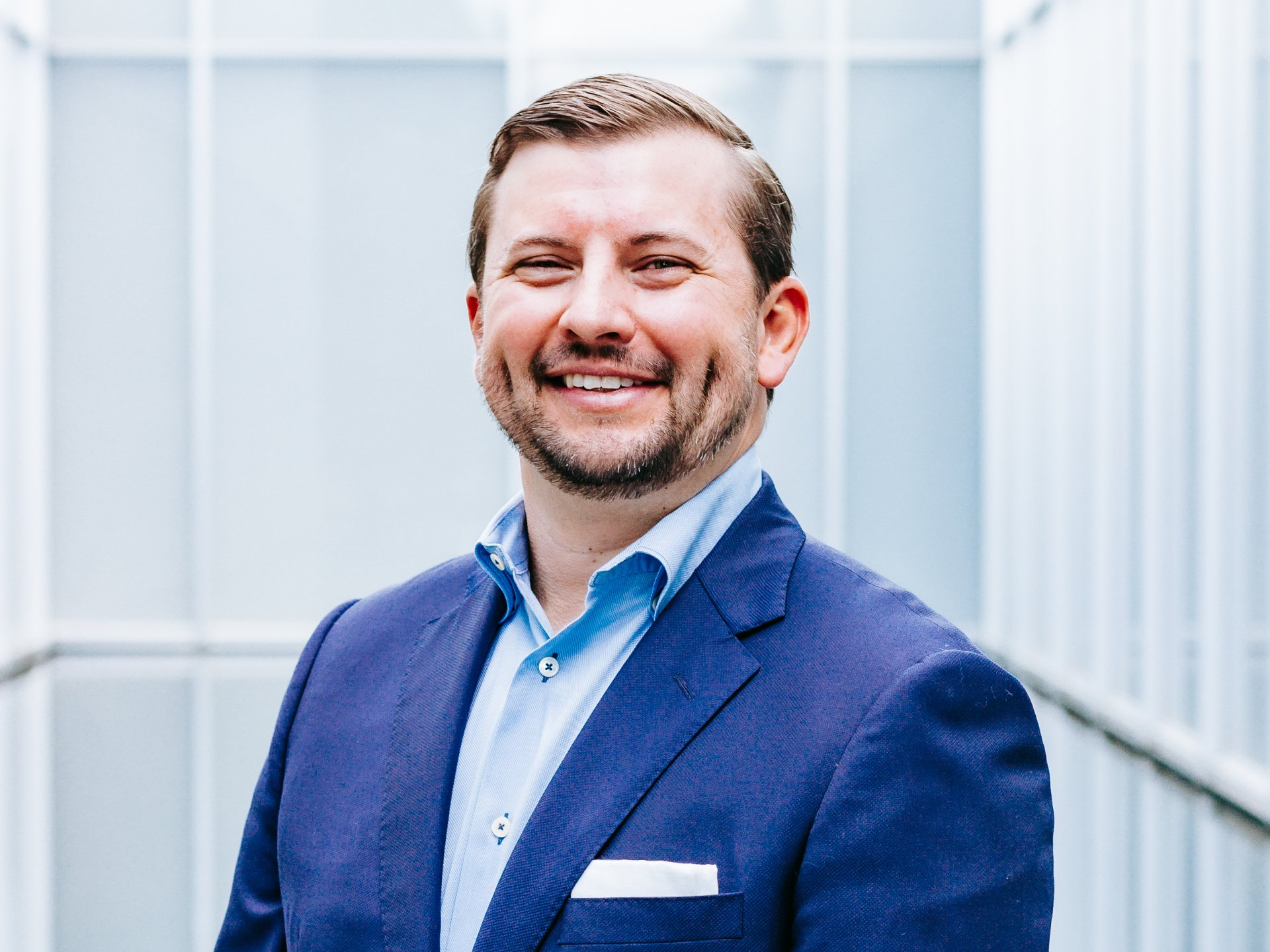 a man in a blue suit and blue shirt is smiling for the camera .