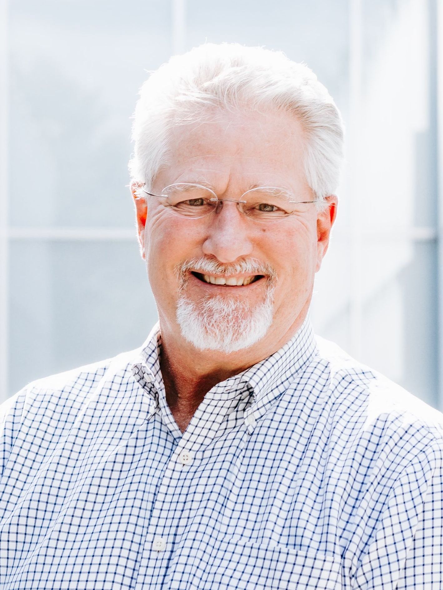 a man with glasses and a beard is smiling for the camera .