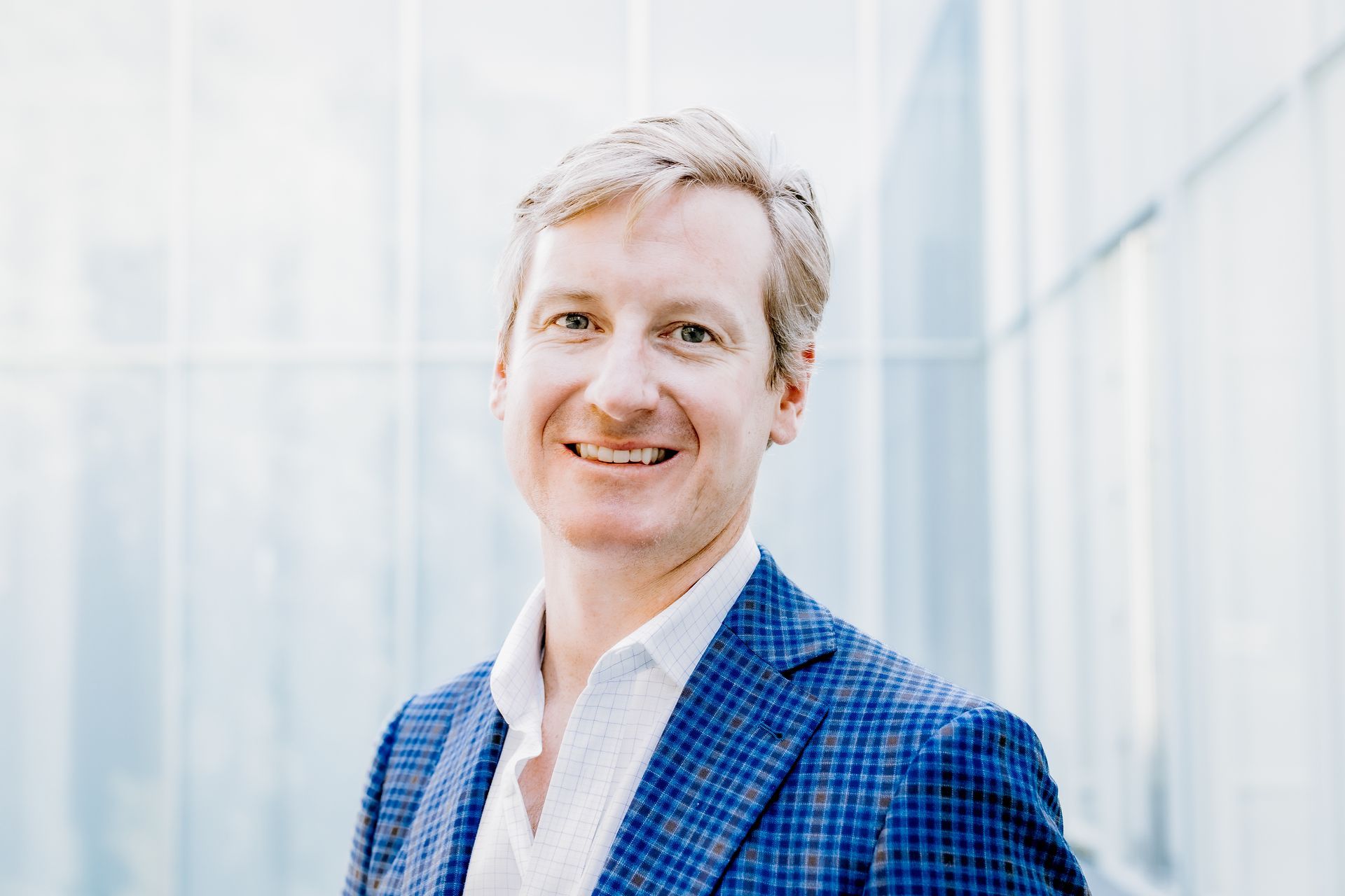 A man in a blue suit and white shirt is smiling for the camera.