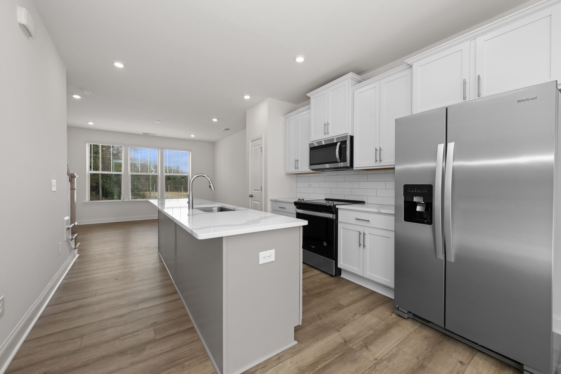 A kitchen in a new home with stainless steel appliances and white cabinets.