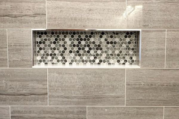A shower stall with a tiled niche in the wall.