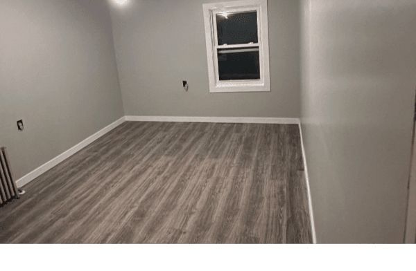 An empty room with a wooden floor and a window.