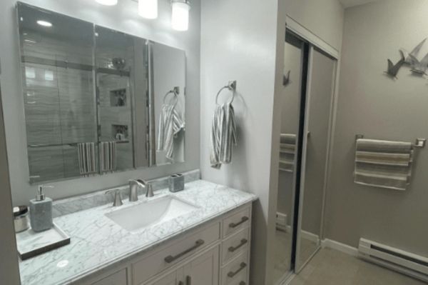 A bathroom with a sink , mirror and shower.