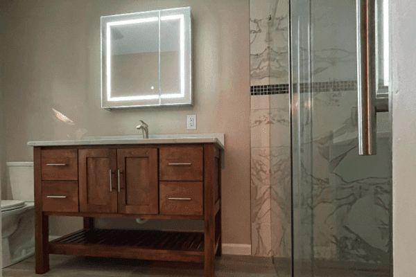 A bathroom with a sink , mirror , toilet and shower.