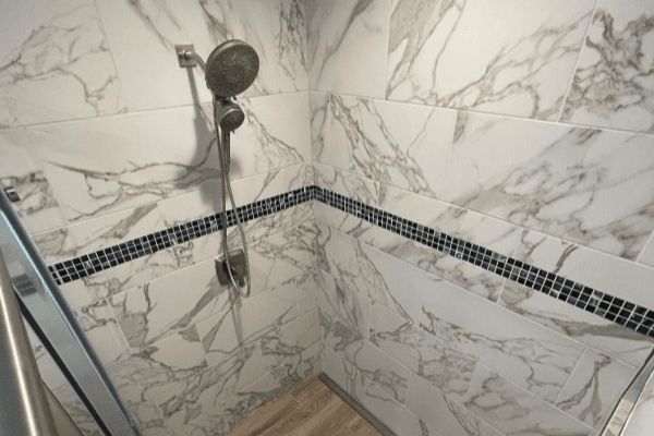 A bathroom with marble tiles and a shower head.
