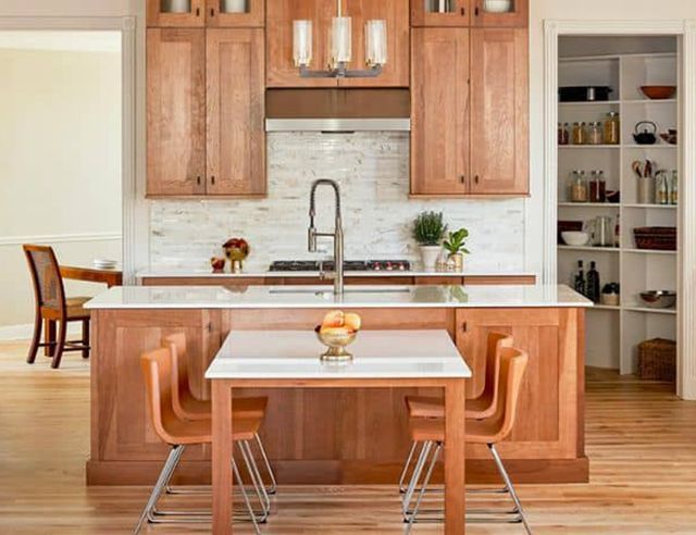 A kitchen with wooden cabinets , a table and chairs.