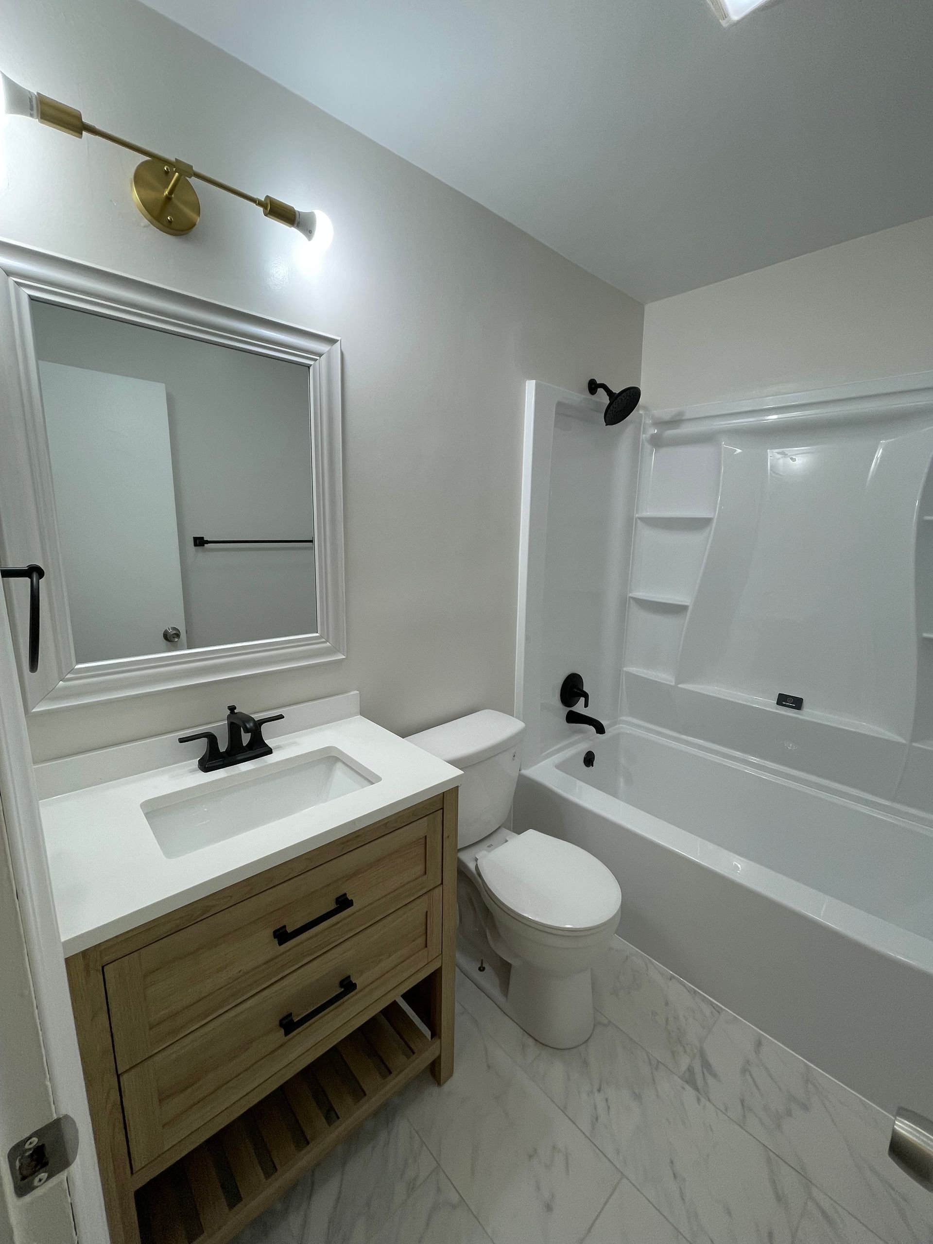 A bathroom with a sink , toilet , tub and mirror.
