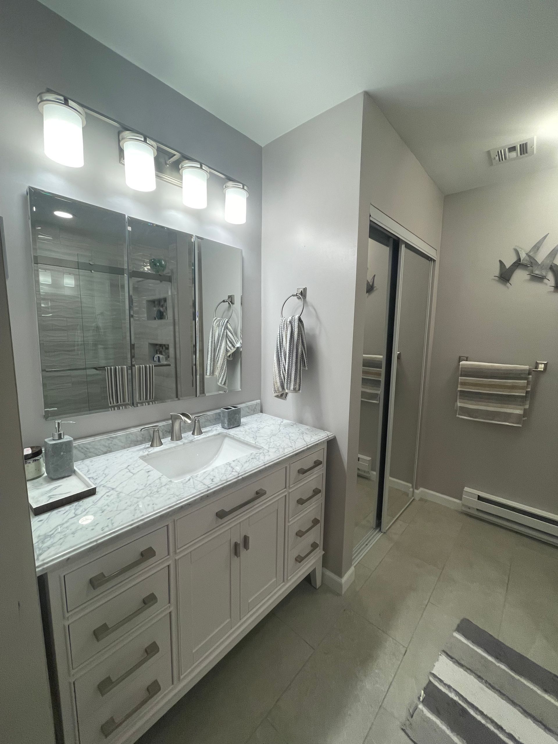 A bathroom with a sink , mirror and towel rack.