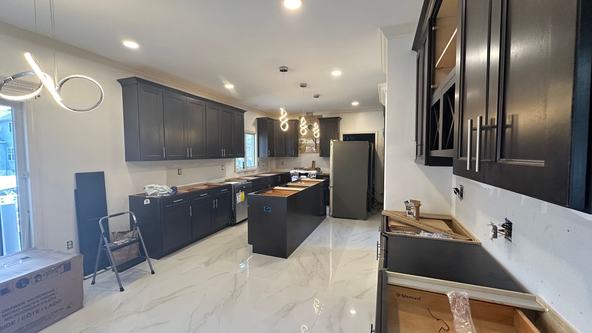 A kitchen under construction with black cabinets and white counter tops