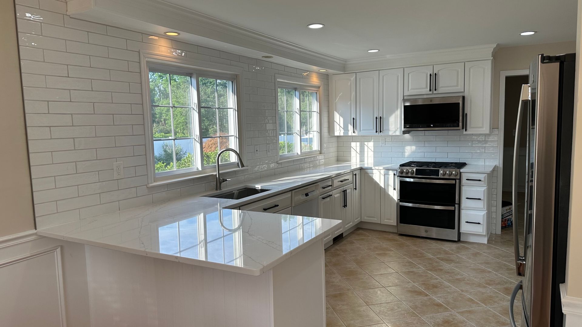 A kitchen with white cabinets , stainless steel appliances , and a large island.